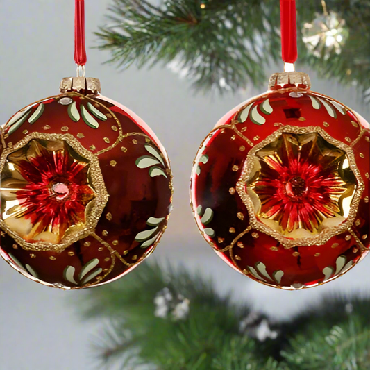 Two red Christmas ornaments with gold and white designs on a white background