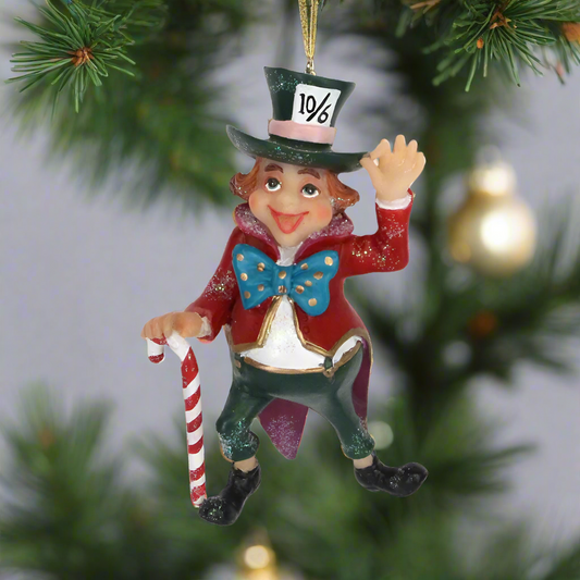 A resin figurine of the Mad Hatter from Alice in Wonderland, dressed in a Victorian top hat and coat, waving, with a candy cane; hanging as a Christmas decoration on a tree.