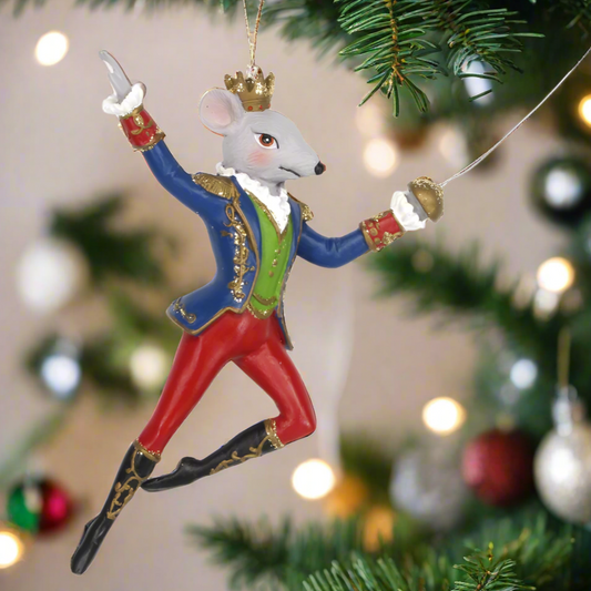 A decorative nutcracker king rat figure in Victorian attire, with a crown, hanging from a Christmas tree.