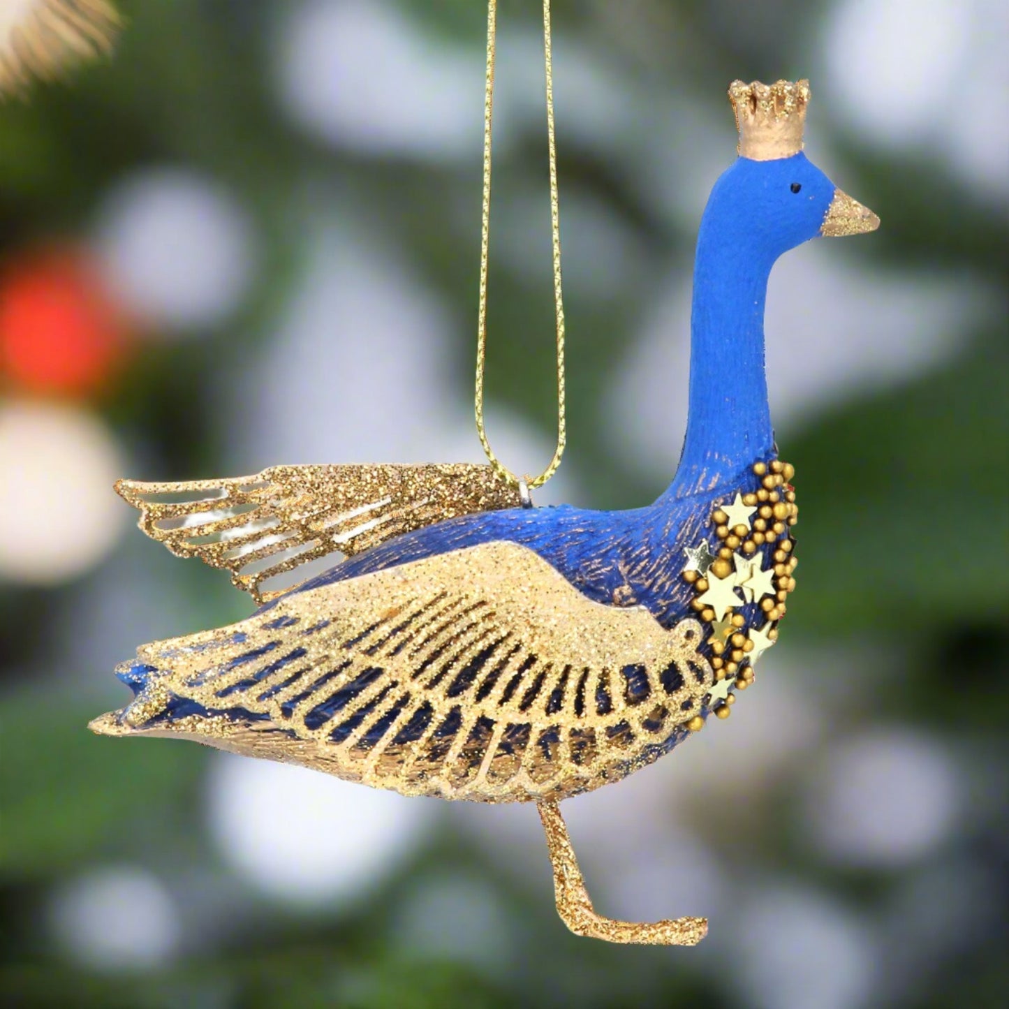 A blue and gold goose-shaped Christmas tree decoration with a golden crown, hanging from a wire.
