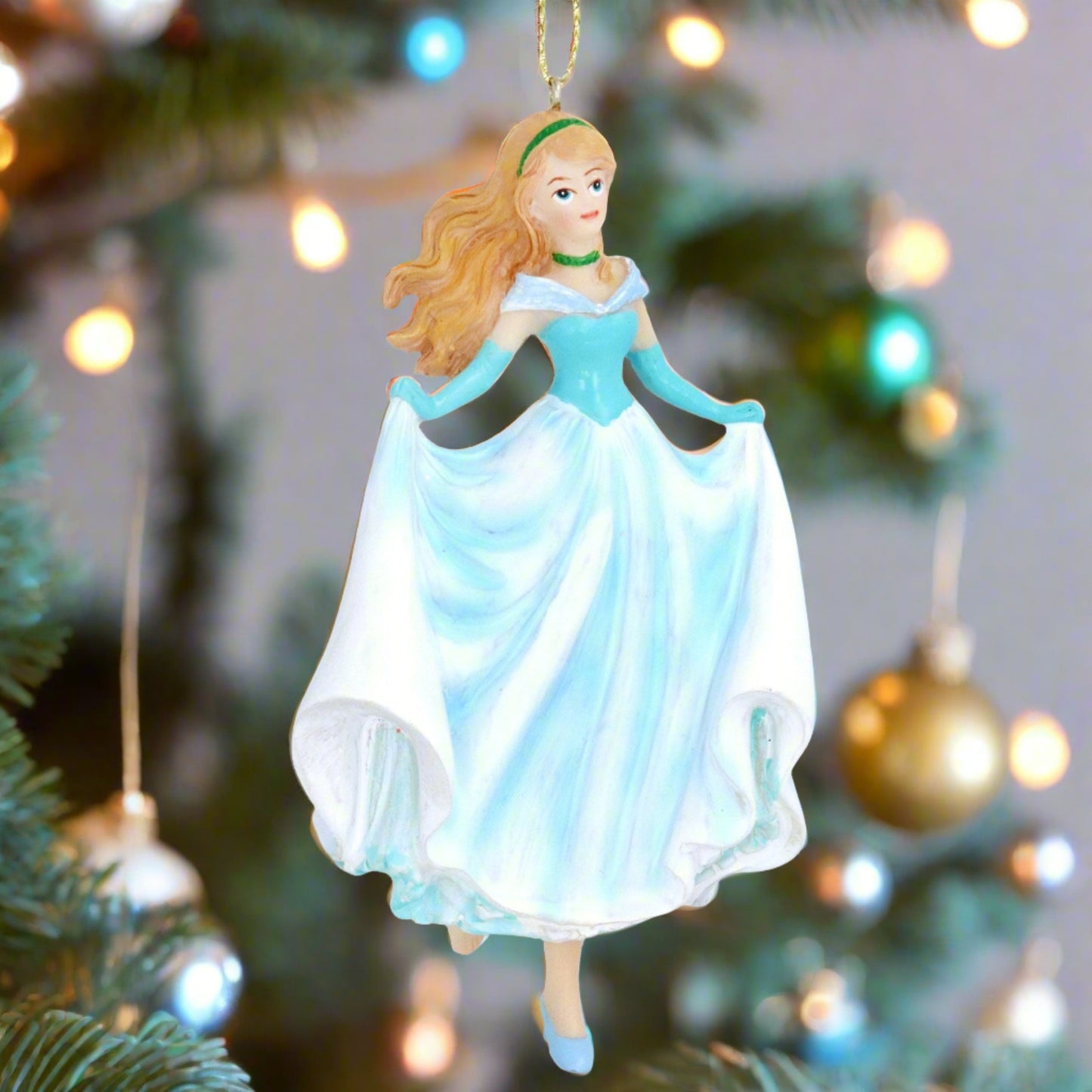A decorative figurine of a woman in a blue dress hanging on a Christmas tree, with a gold wire for hanging and a resin material.