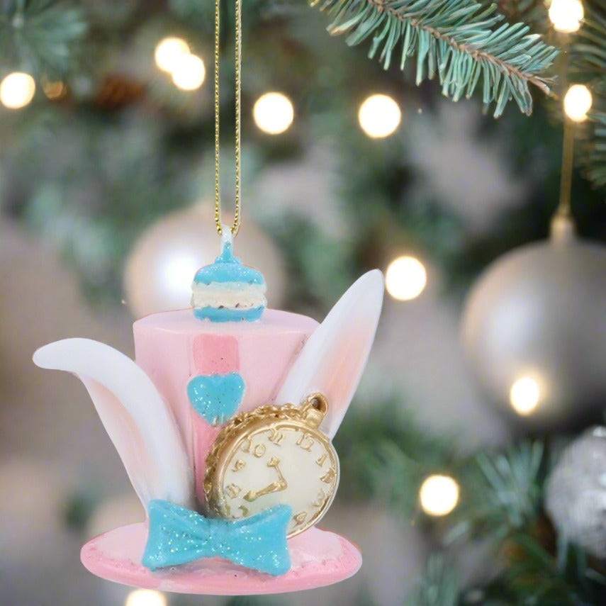 A pink, blue, and white resin hanging decoration featuring a hare (rabbit) hat with ears, a cake design, and a clock.