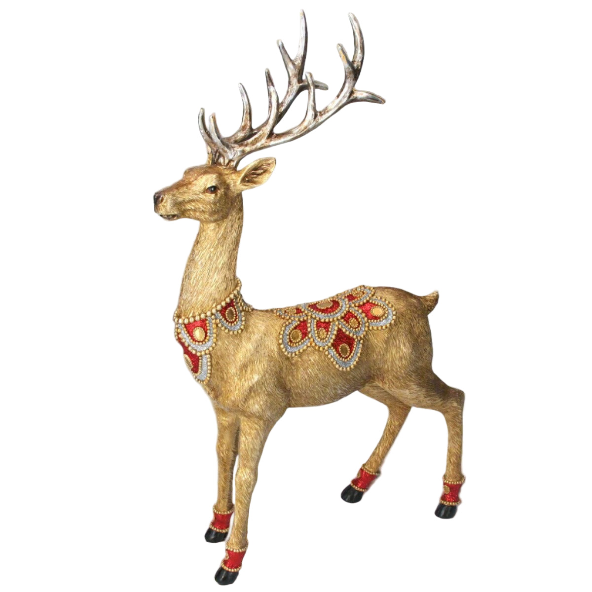 A gold-colored Christmas stag ornament adorned with red jewels on its saddle, collar, and anklets, placed against a backdrop of Christmas lights and a pine tree.