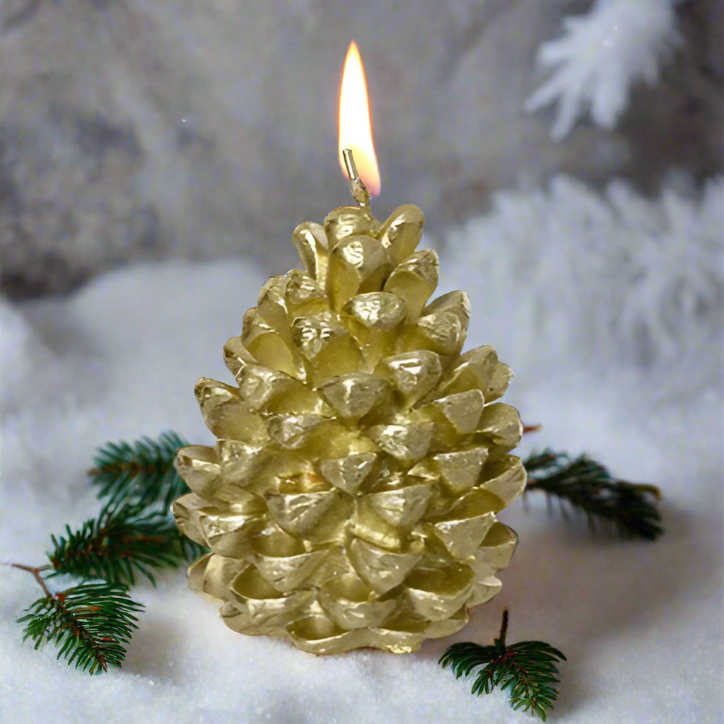 Gold pine cone candle with a flame on a snowy background