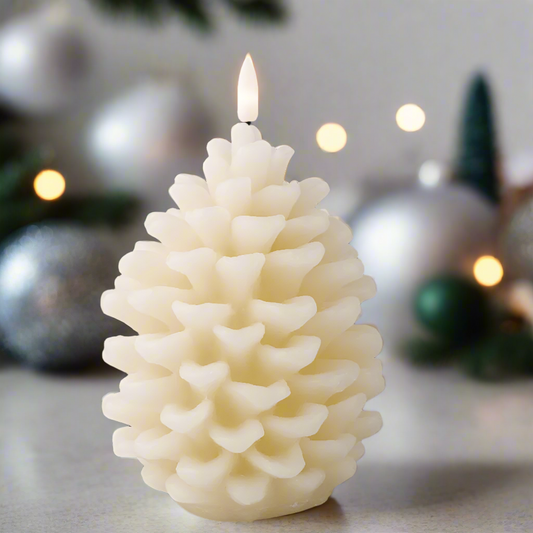 A cream pinecone-shaped LED candle with a smooth finish, surrounded by Christmas decorations including lights and pine cones.