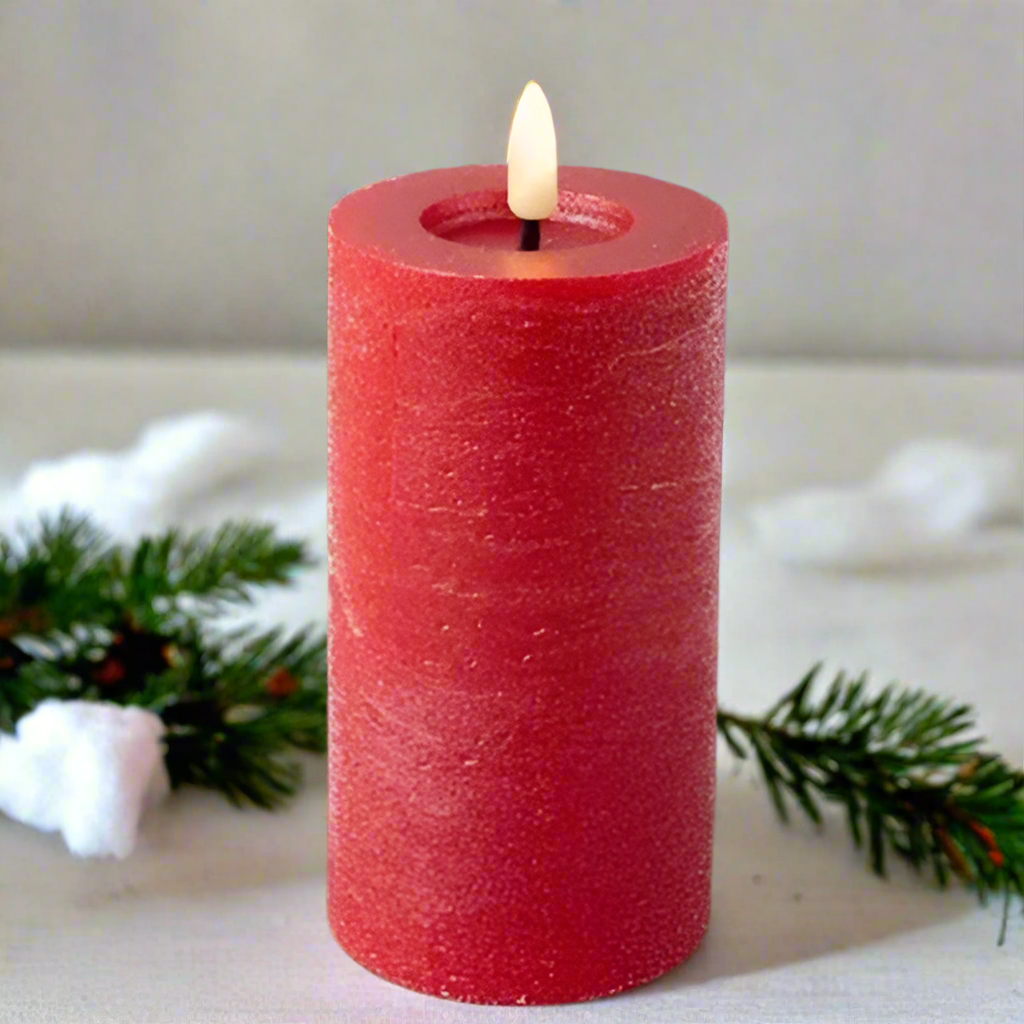 Red candle with a lit wick on a light background with decorative elements
