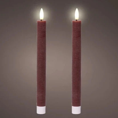 A pair of oxblood red flat top LED wax dinner candles with a warm white glow, set against a grey background.
