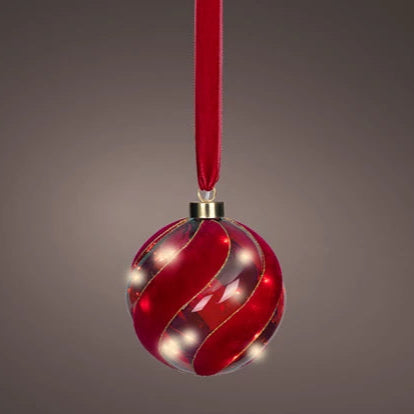 Red Christmas ornament with wavy pattern and gold ribbon on a gray background