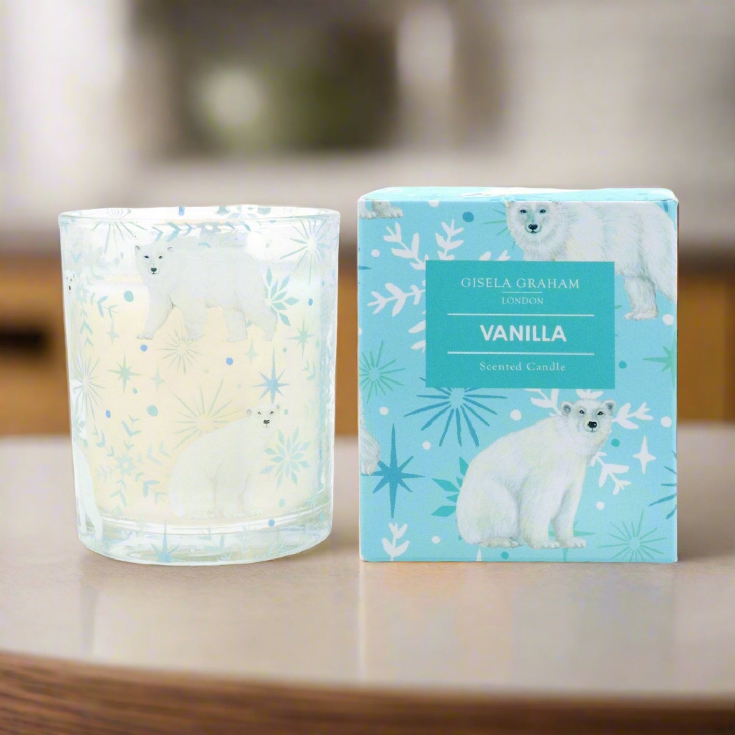 A clear glass candle with a vanilla scent, featuring a polar bear design on the label, alongside its blue packaging box with the same design.