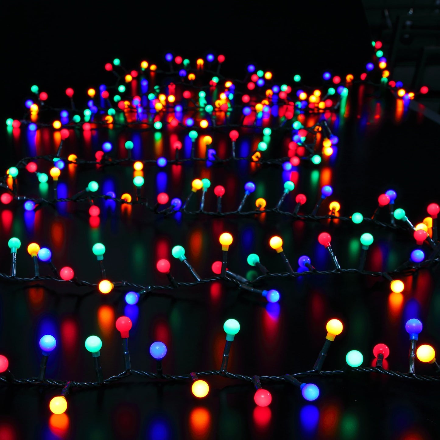 A string of multicolored Christmas lights with various berry-shaped LEDs on green cables.