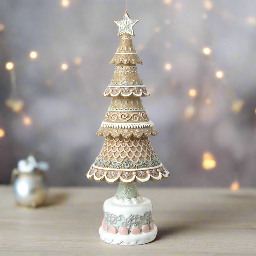 A decorative gingerbread Christmas tree with multiple layers, featuring beige, white, and multicolor patterns, topped with a star, on a white base.