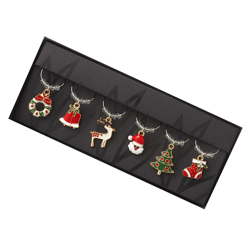 A set of six Christmas-themed wine glass charms displayed in a black box, including holiday designs such as a reindeer, Santa, Christmas tree, and stocking.