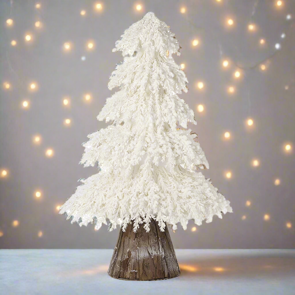 A white artificial Christmas tree with a rustic wooden base.