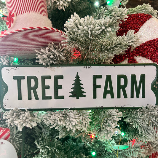 Decorative sign with 'TREE FARM' on a Christmas tree with stockings and lights.