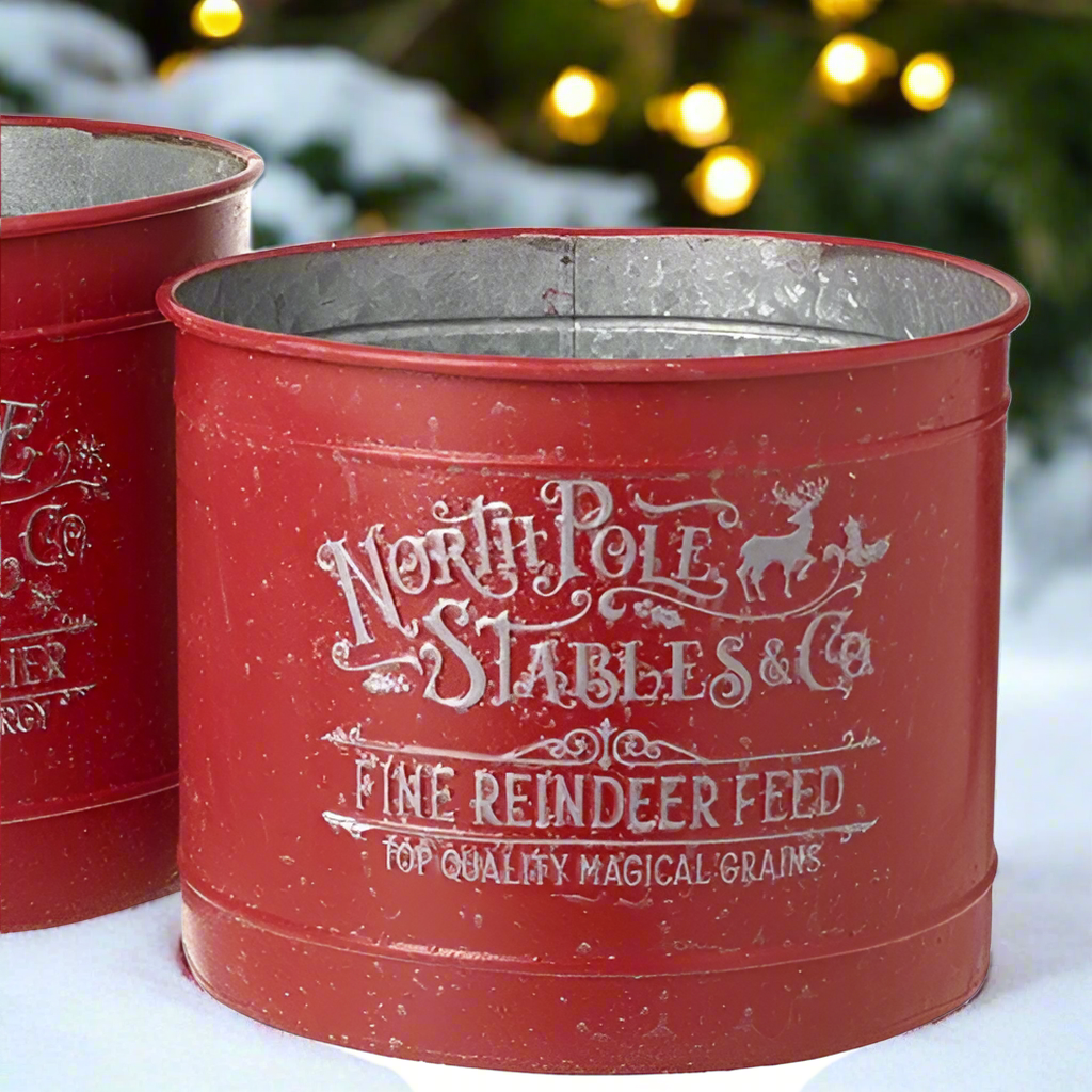 Red metal feed container with 'North Pole Stables & Co' text on a snowy background
