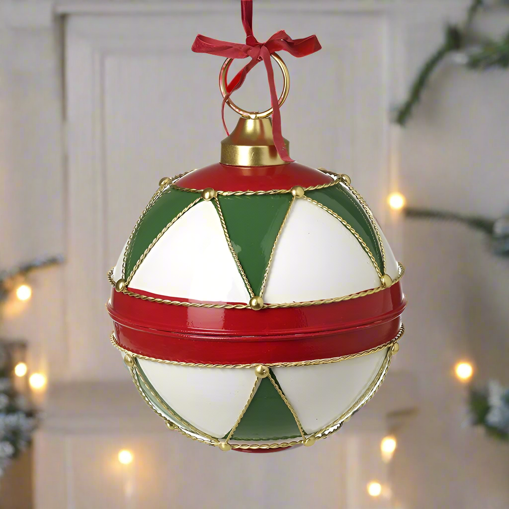 A large round Christmas ornament with red, green, white, and gold geometric patterns, featuring a gold top and a red ribbon hanger.