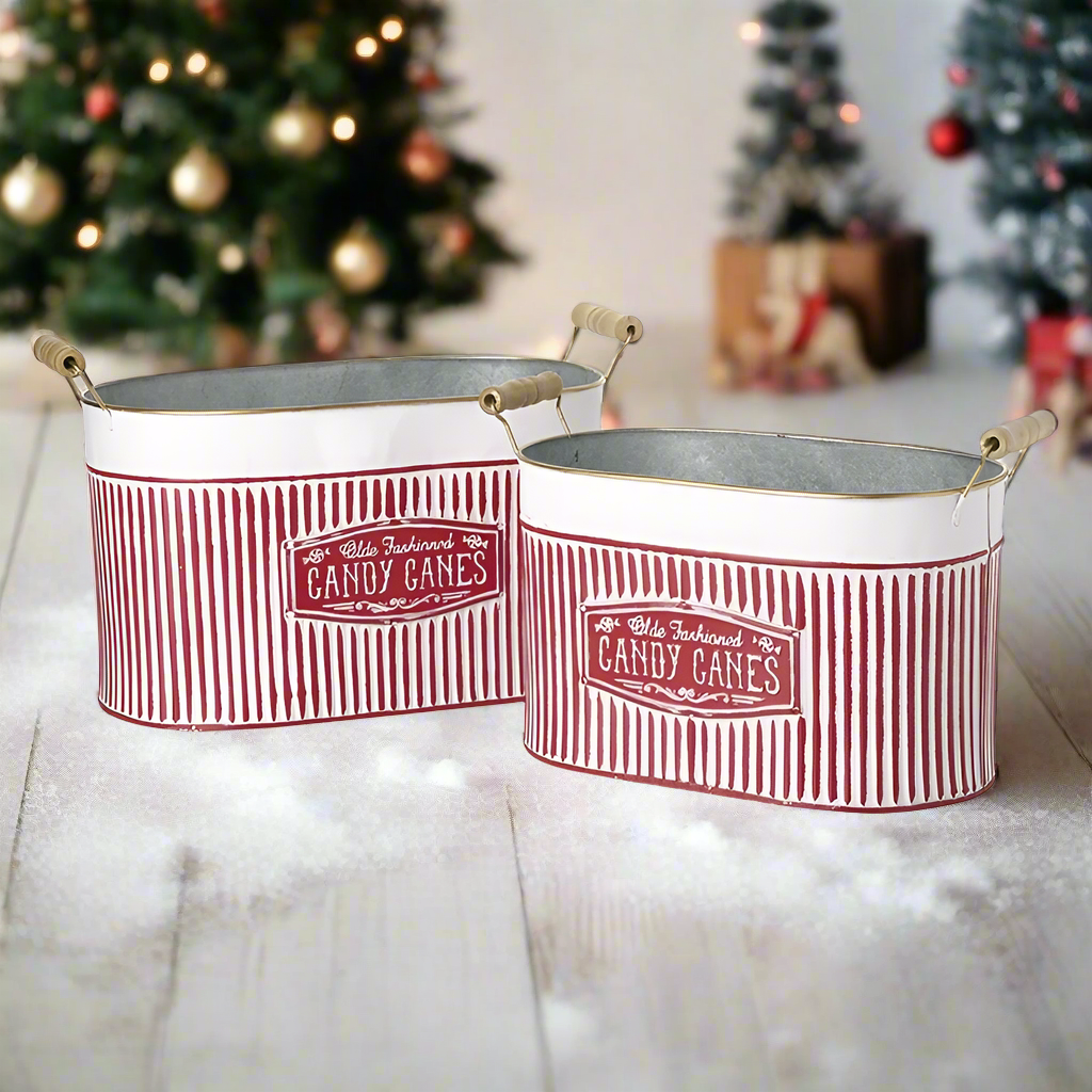 Two red and white striped metal buckets with 'CANDY CANES' text on them, designed for holiday decoration.