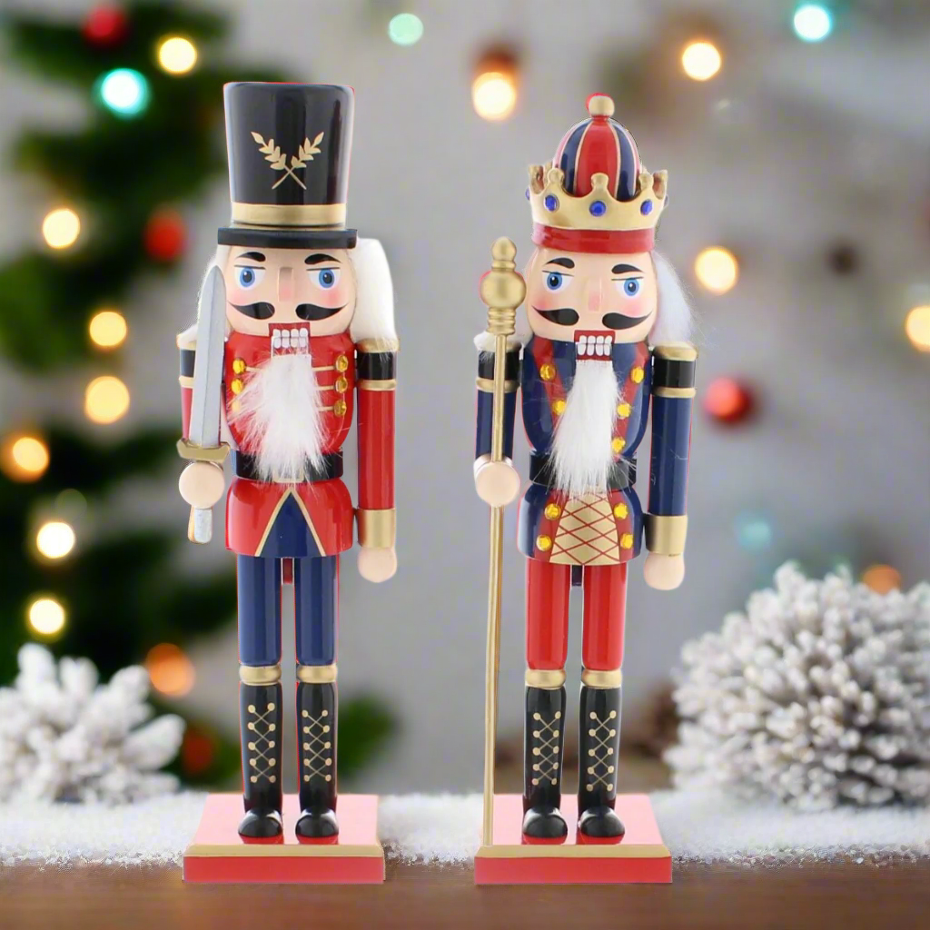 Two traditional Christmas nutcrackers decorations, one with a top hat and the other with a crown, in blue and red uniforms, holding swords and staffs, standing on red bases.
