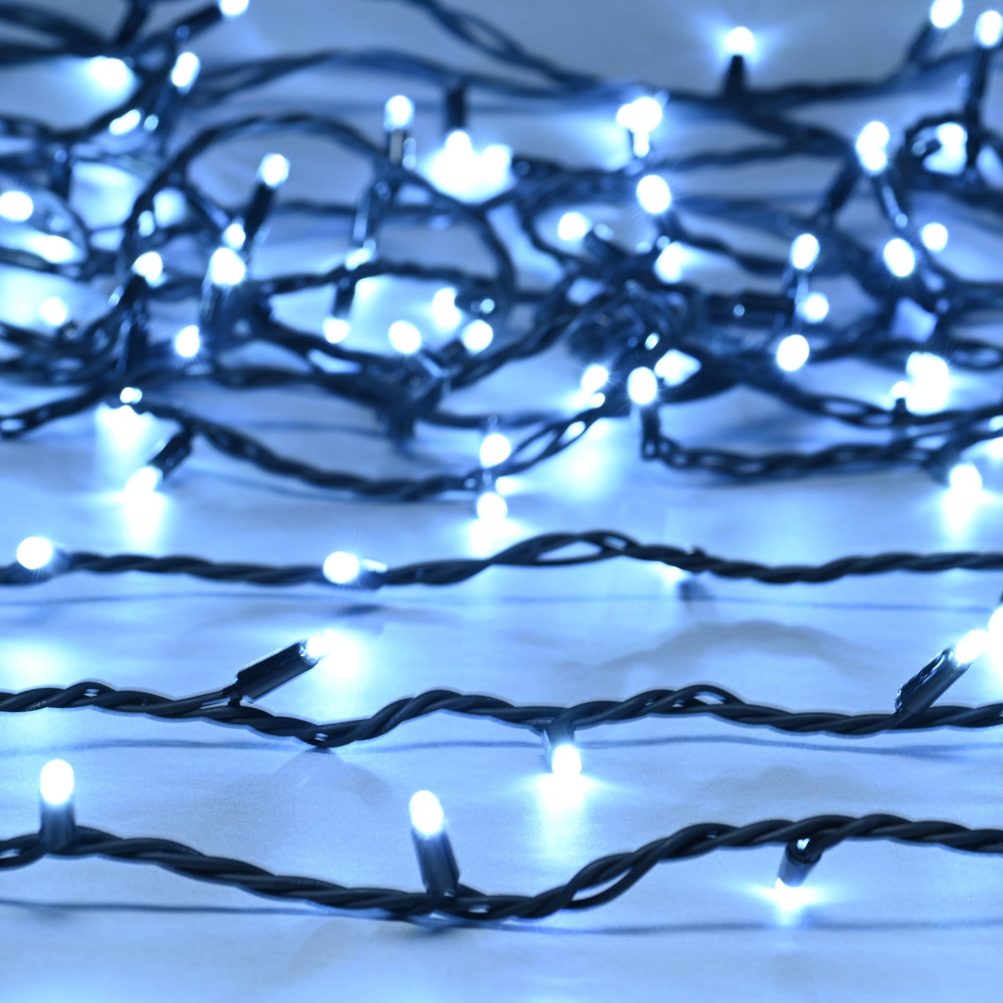 A close-up of heavy duty connectable white Christmas lights with visible bulbs on black cables.