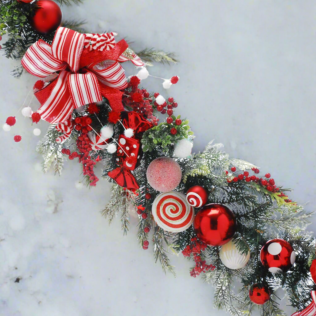 candy cane Christmas garland with baubles bows and berries in green foliage.
