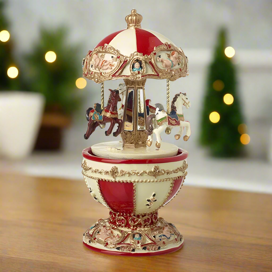 A decorative Egg Shape Christmas Merry Go Round music box with traditional carnival horses rotating inside, displayed on a table with festive decorations in the background.