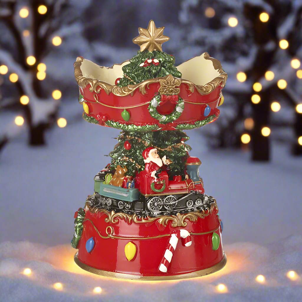 A decorative Christmas ornament featuring Santa Claus sitting on a train with a spinning base, decorated with a Christmas tree and festive elements.