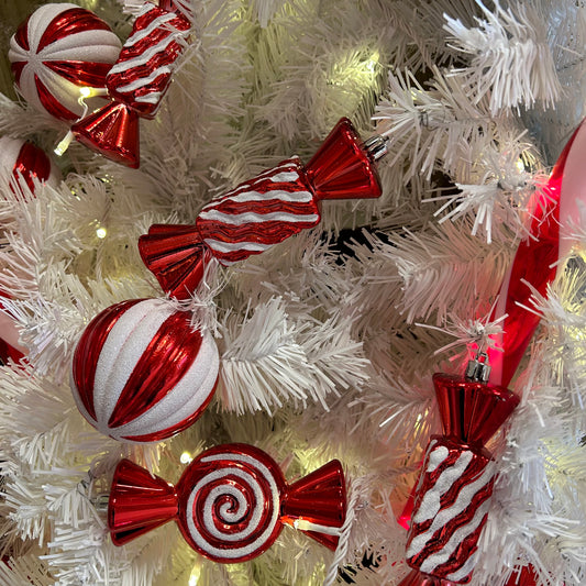A set of striped candy cane Christmas baubles in red and white, displayed on a Christmas tree with lights.
