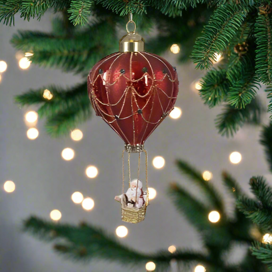 A red hot air balloon with Santa Claus and a Christmas tree decoration, featuring gold and red colors with a glass dangling ornament.