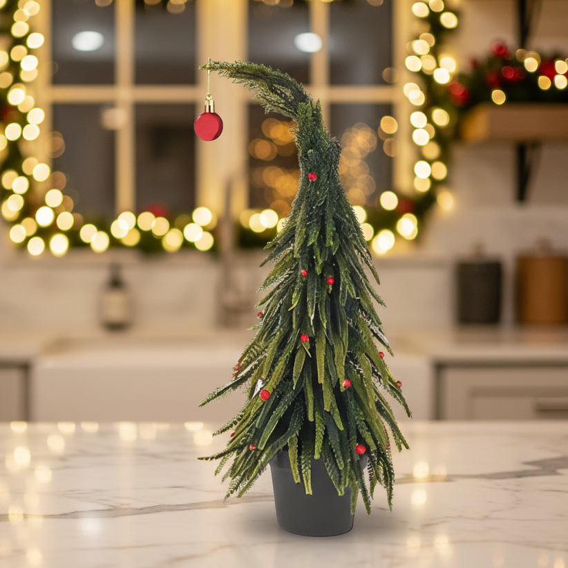 Small potted Christmas tree with red ornaments in a kitchen setting with blurred lights in the background.
