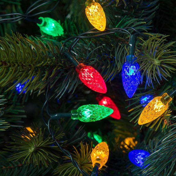 A Christmas tree decorated with multicolored faceted cone lights, varying in color from green, yellow, red, blue, and white, set against a dark background.
