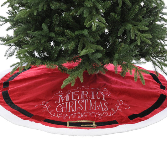 A red felt Christmas tree skirt with a 'Merry Christmas' message and a Santa belt design, placed under a green Christmas tree.