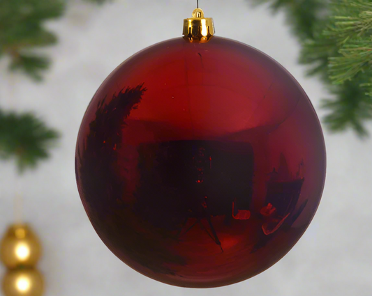 Red Christmas ornament with black silhouettes on a white background