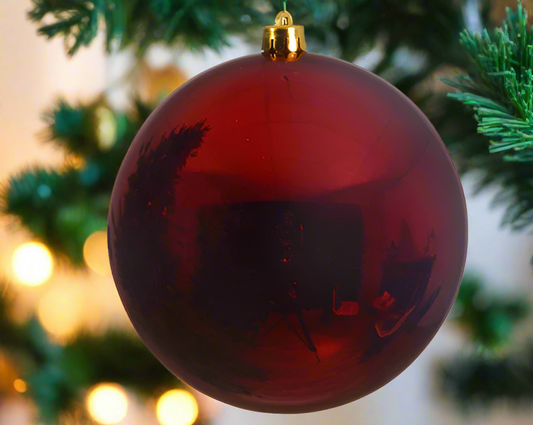 Red Christmas ornament with black silhouettes on a white background