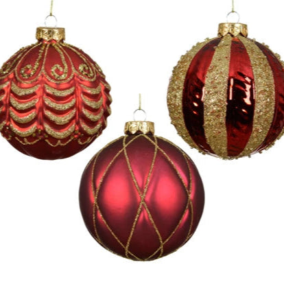 Three red and gold Christmas ornaments on a white background