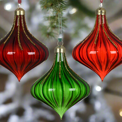 Two red and green glass ornaments hanging against a white background