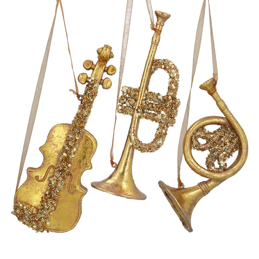 Decorative ornaments shaped like a violin, trumpet, and horn with glittery texture on a white background.