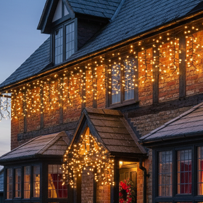 A string of warm white LED icicle berry lights with black wires, designed for indoor or outdoor decoration.