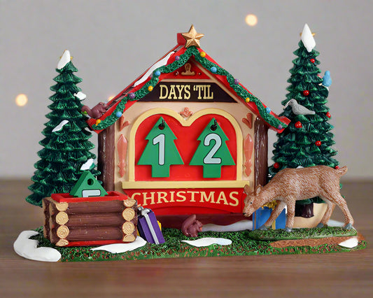 Christmas-themed decorative cabin with a countdown to Christmas display, surrounded by trees and a deer.