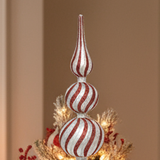 Decorative Christmas tree topper on a decorated Christmas tree with lights and ornaments.