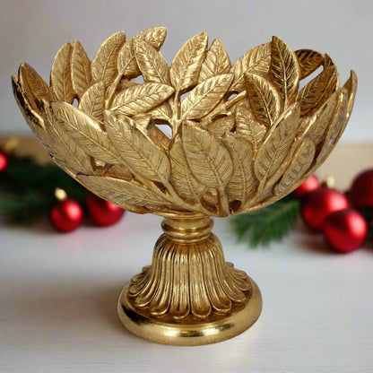 A gold leaf design festive bowl on a pedestal, displaying a decorative pattern resembling leaves.