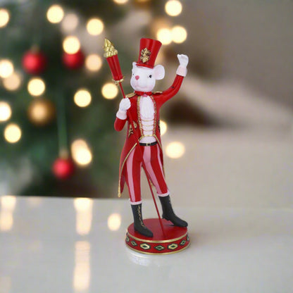 A Captain Mouse Christmas ornament, with red and white striped uniform and a hat, standing in front of a Christmas tree.