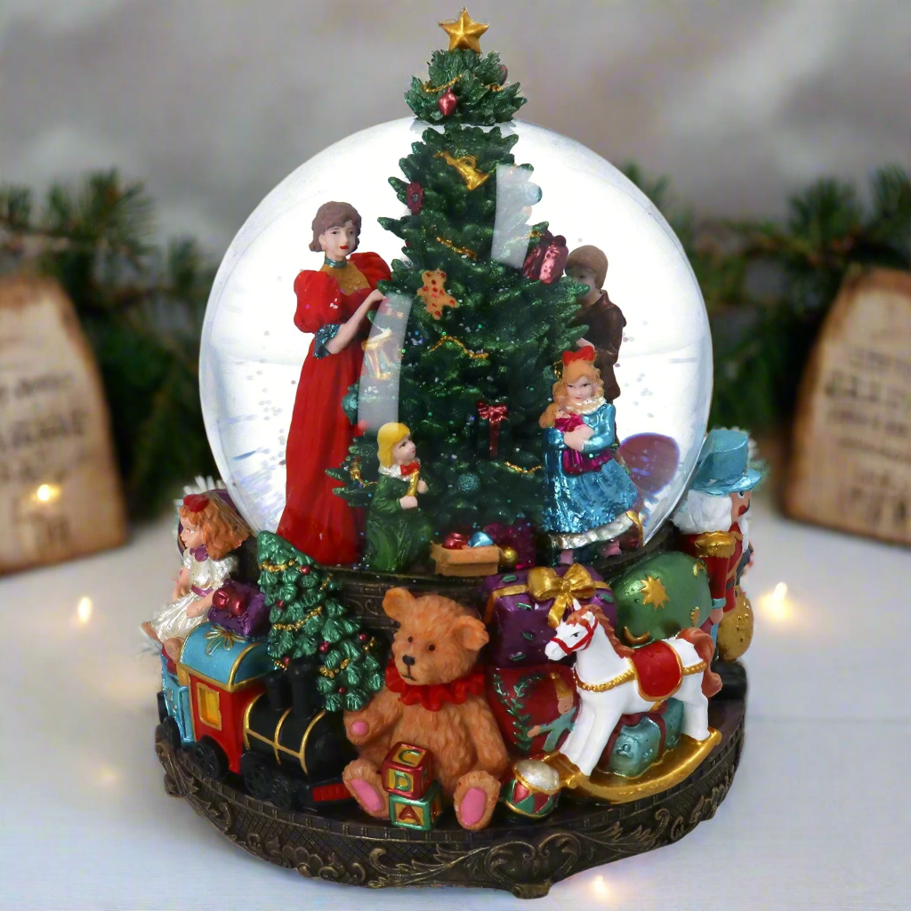 Decorative Christmas snow globe with figures and a tree inside.