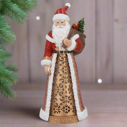 Decorative figure of a traditional Santa Claus holding a bundle of sticks and a small tree on a white background.