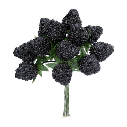 A bunch of artificial blackberry picks tied together on a stem, against a white background.