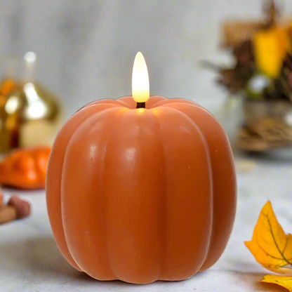 Pumpkin-shaped candle with a lit flame on a neutral background