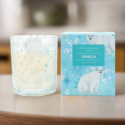 A clear glass candle with a vanilla scent, featuring a polar bear design on the label, alongside its blue packaging box with the same design.