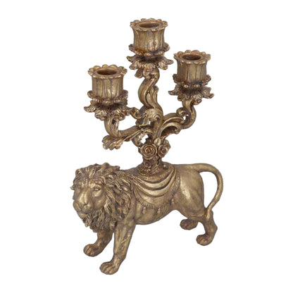 A gold-colored lion-shaped candelabra with three candle holders, positioned on a table with a blurred festive background.