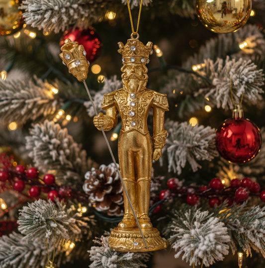 Gold Nutcracker ornament on a decorated Christmas tree with red and gold ornaments.