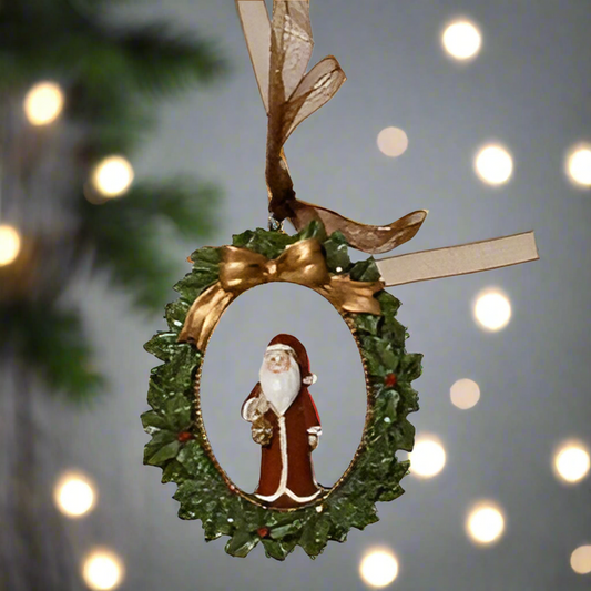 Decorative Christmas ornament with Santa Claus in a wreath on a blurred festive background.