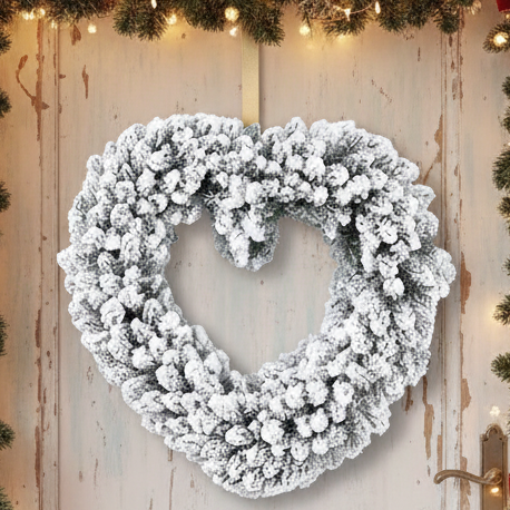 A heart-shaped wreath with green foliage and a snowy effect, designed for indoor use.